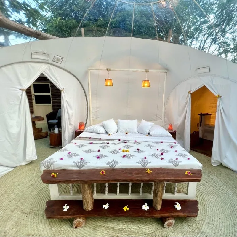 The king bed inside the transparent dome, dressed with flower petals and open to the trees overhead